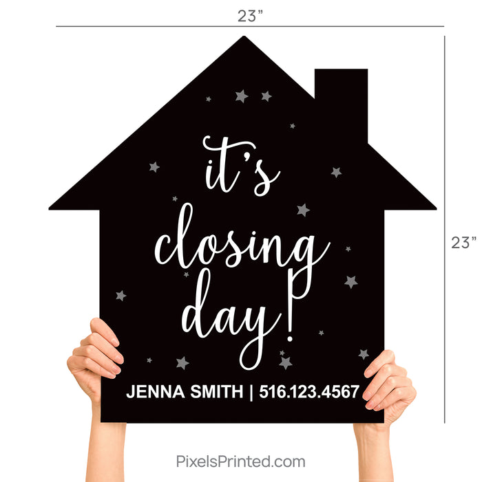 Realtor and client standing at a title company holding an It's Closing Day house-shaped sign.